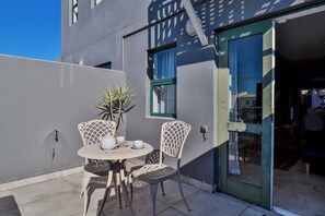 Relax in this serene outdoor seating area with a round table, two chairs, and a potted plant.