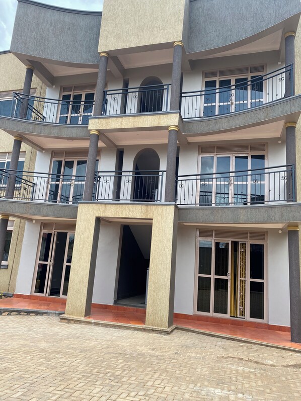 A multi-story building with balconies, large windows, and a tiled entrance area. - Lee Urban Homes (Kampala)