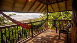 A covered outdoor area with a view of the beach, a hammock, and two chairs. - Ostional river  (Nuquí)