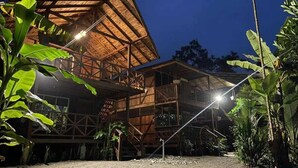 A wooden building with a sloped roof and multiple levels, surrounded by lush greenery. - Ostional river  (Nuquí)