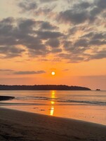 Una playa al atardecer, con el sol reflejándose en el agua.