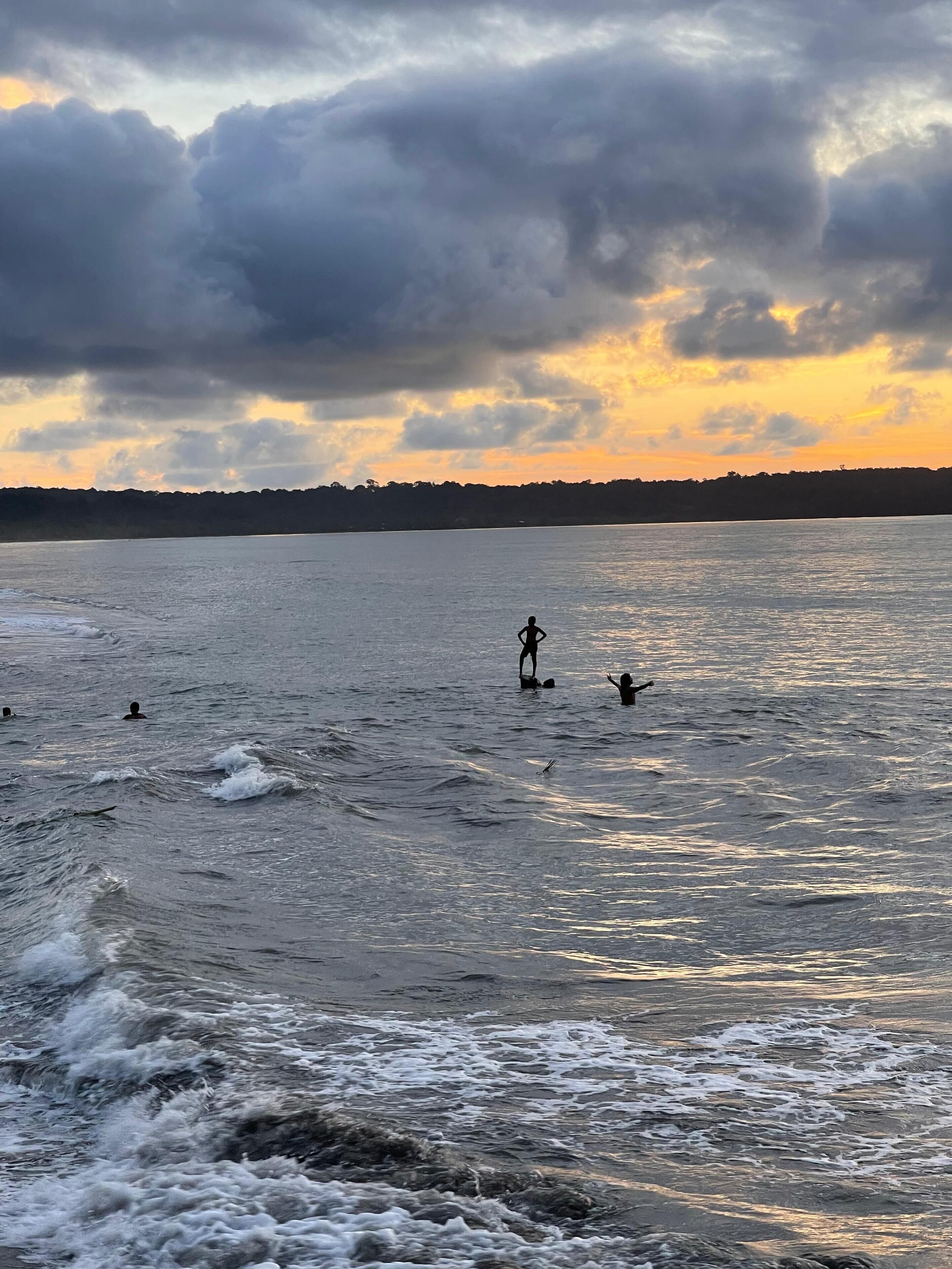 Escena de playa con olas y un atardecer.