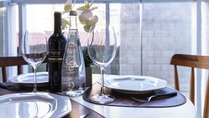 A dining table with wine bottles, glasses, and a vase with flowers. - Piscina academia metro  Brazilian Corner (São Paulo)