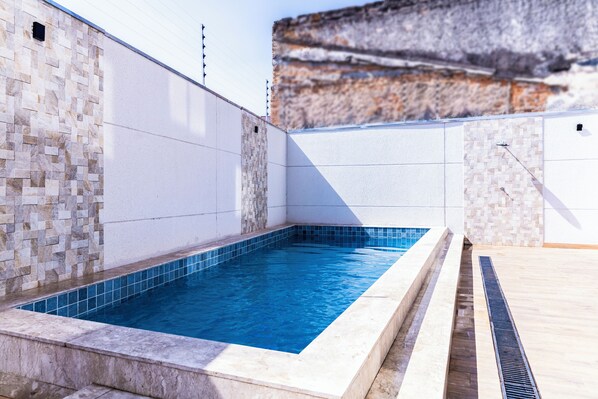 Une piscine aux murs recouverts de carreaux et un mur d’accent en pierre.