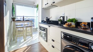 A modern kitchen with a large window, wooden stools, and a view of the city. - Piscina academia metro  Brazilian Corner (São Paulo)