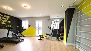 Une salle de sport moderne équipée de machines de cardio, de bancs de musculation et d’une barre de traction.