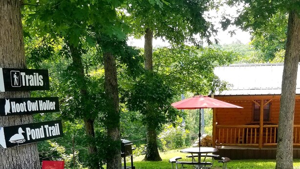 En plats för picknick med ett bord och stolar, ett rött parasoll och en skylt som visar var vandringslederna börjar.