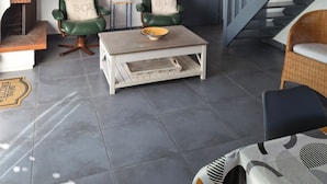 Un salón espacioso con chimenea, dos sillones de cuero verde, una mesa de centro y una escalera.