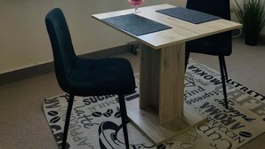 A room with a wooden table, two chairs, a potted plant, and a window with sheer curtains. - Quartier 2 - Ferienwohnung Zentral Gelegen (Bremerhaven)
