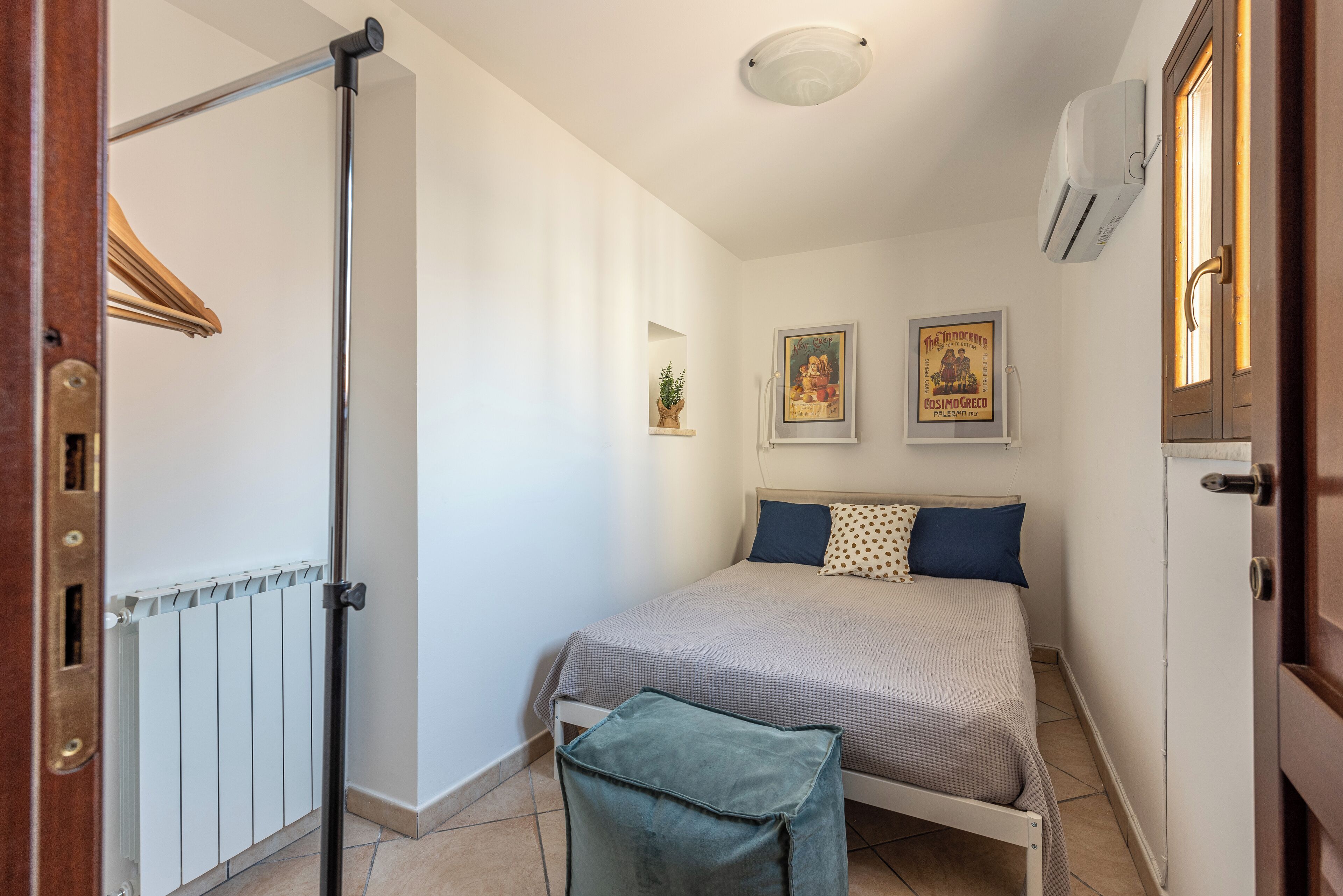 Una camera da letto con un letto, un termosifone, una porta e un condizionatore d'aria a muro.