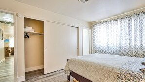 Une chambre à coucher avec un lit, une armoire et une fenêtre ornée de rideaux à motifs.