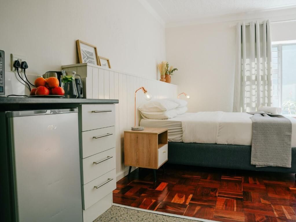 Un dormitorio con cama, mesita de noche y escritorio con computadora y fruta.