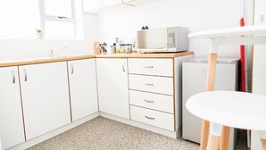 Een moderne keuken met witte kastjes, een magnetron en een eettafeltje.