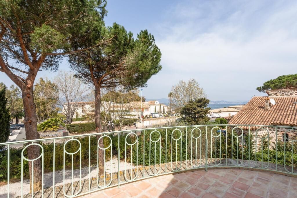 A terrace with a curved metal railing, overlooking a residential area with houses and trees.