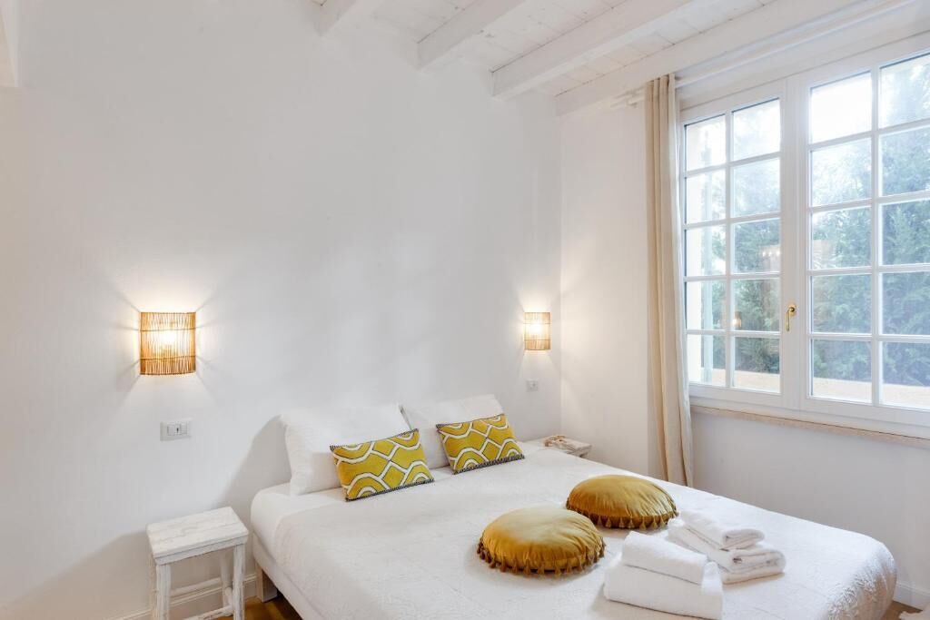 A bedroom with a bed, bedside lamps, a nightstand, and a window with a view.