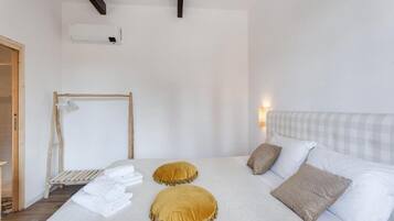 A bedroom with a bed, pillows, a wooden ladder, and a white wall.