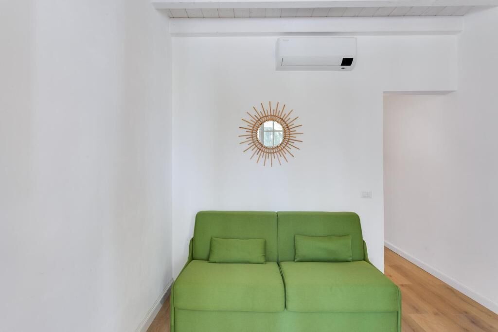 A green sofa in a room with white walls and a wooden floor.