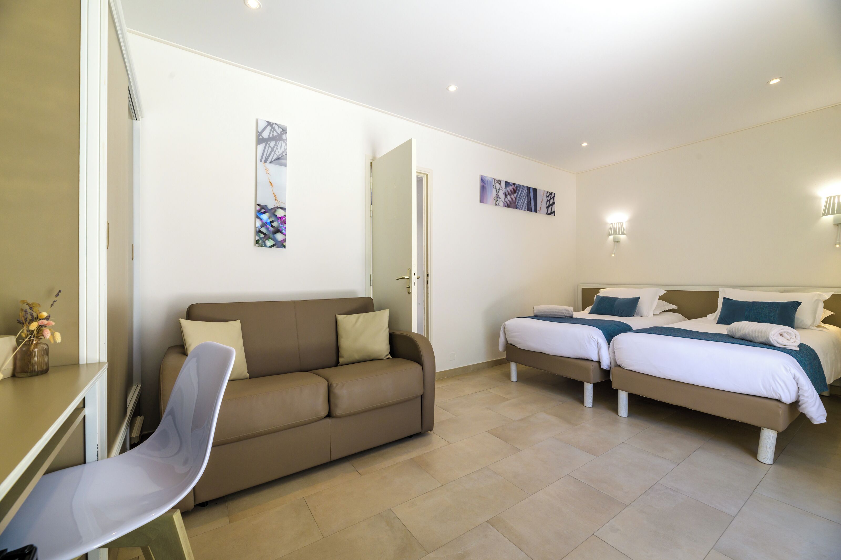 Een hotelkamer met een bank, twee bedden, een bureau en kunst aan de muren.