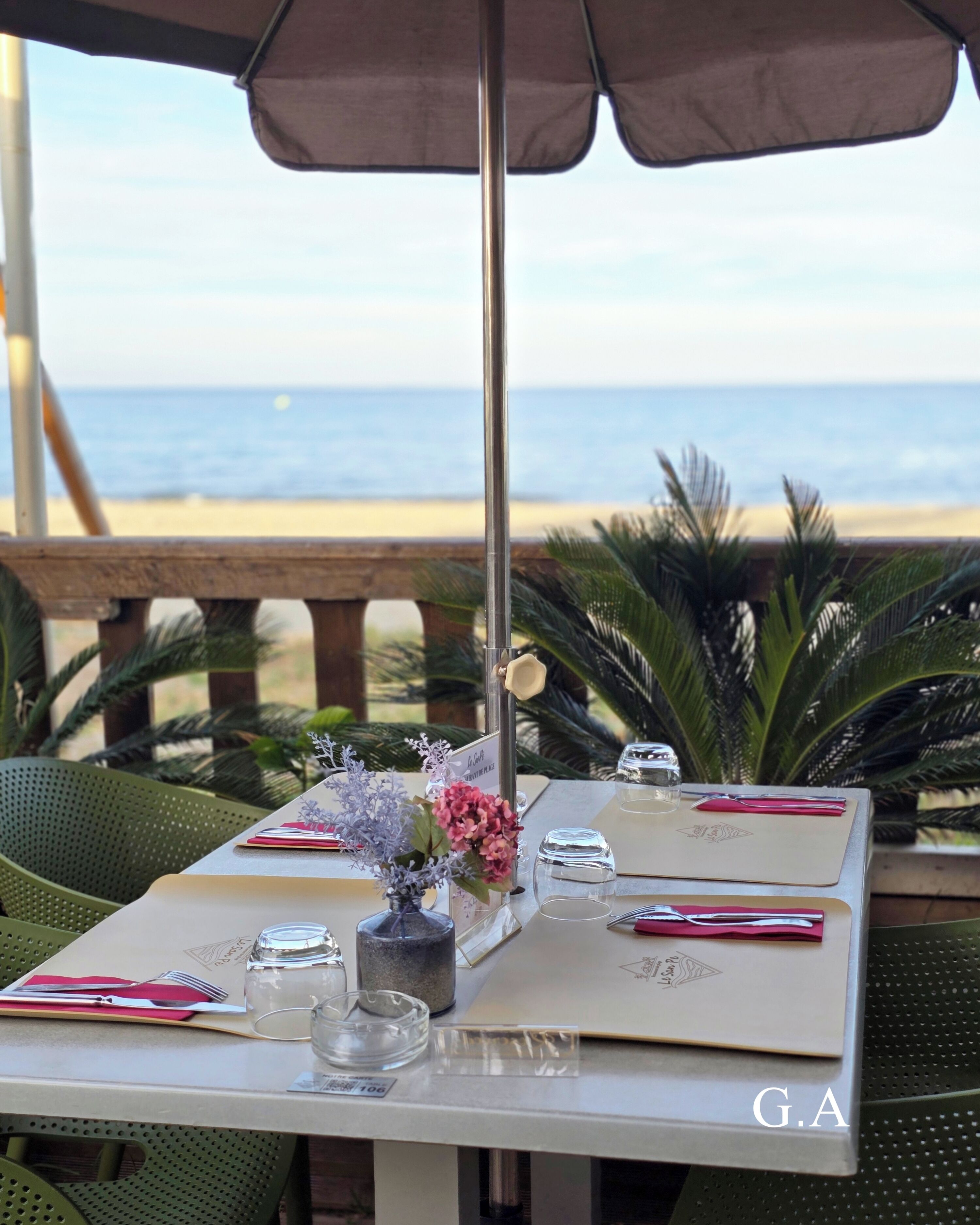 Mesa dispuesta para dos con vista a la playa y al océano.