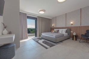 A modern hotel room with a large bed, a desk, and a view of greenery. - Private & Modern 4BR Villa, Heated Pool, Jacuzzi, and Gaming room, Near Zadar (Bibinje)