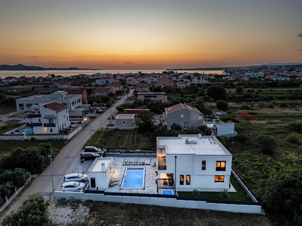 A modern residential area with houses, a swimming pool, and a road. - Private & Modern 4BR Villa, Heated Pool, Jacuzzi, and Gaming room, Near Zadar (Bibinje)