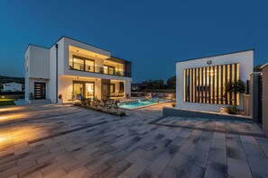 A modern two-story house with a swimming pool, outdoor seating, and a well-lit patio area. - Private & Modern 4BR Villa, Heated Pool, Jacuzzi, and Gaming room, Near Zadar (Bibinje)