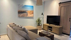 A modern living room with a sofa, a TV, a wooden cabinet, and a painting on the wall. - Tranquil Cottage Retreat - Malanshof, Randburg (Johannesburg)