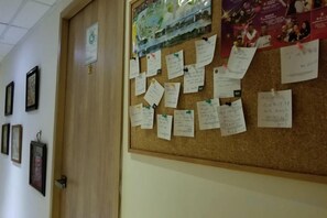 A bulletin board with handwritten notes and a framed picture on the wall. - Leisure Hostel (Hong Kong)