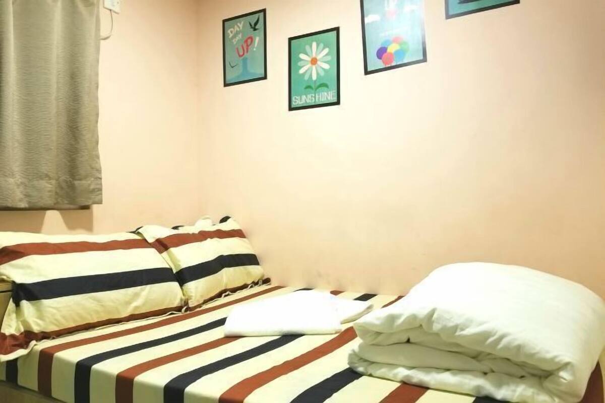 A single bed with striped bedding, a white pillow, and a wall with three framed pictures.