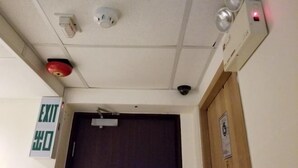 A ceiling with smoke detectors, a fire alarm, and a light switch. - Leisure Hostel (Hong Kong)