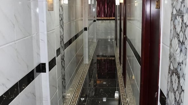 A corridor with marble walls and a patterned floor, leading to a room with a red curtain. - Leisure Hostel (Hong Kong)