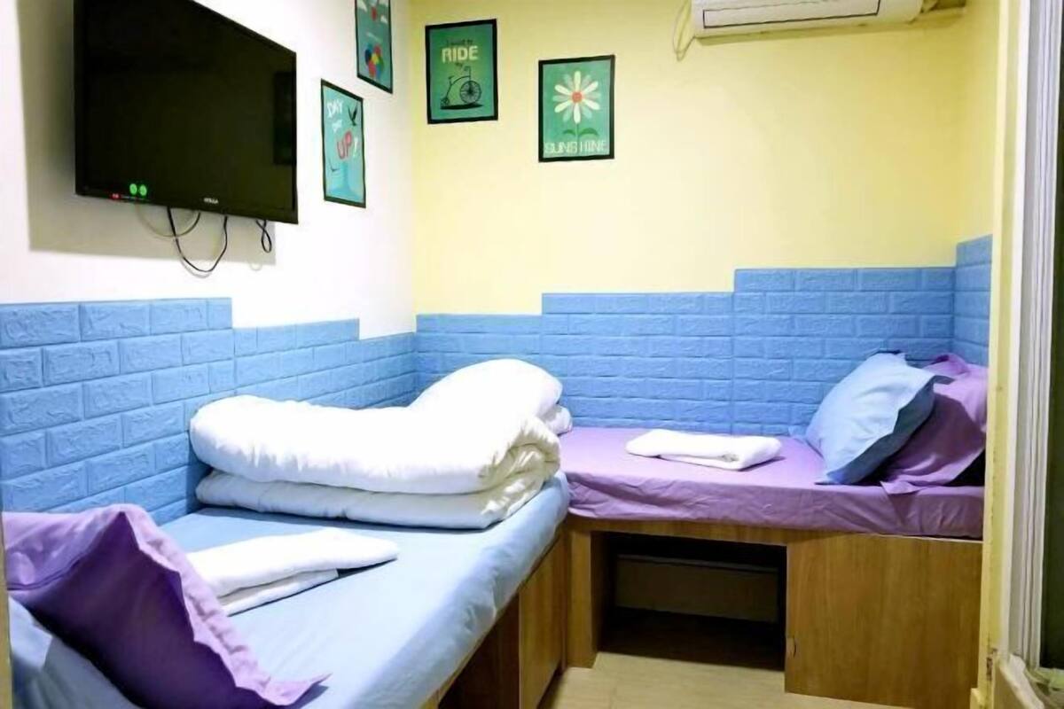 A room with two beds, a TV, and wall art.