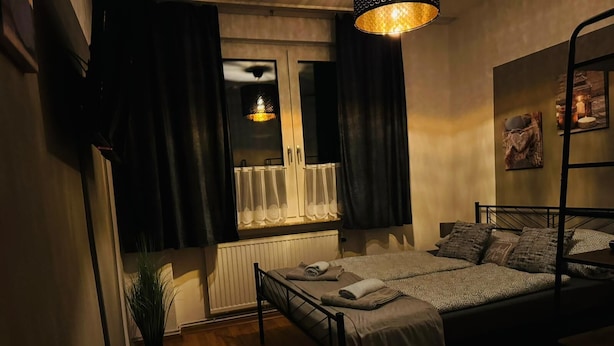 Una camera accogliente con un letto, una finestra con tende, un termosifone e una lampada a sospensione.