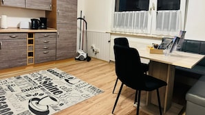 Una cucina compatta con mobili in legno, un tavolo da pranzo e una sedia nera.