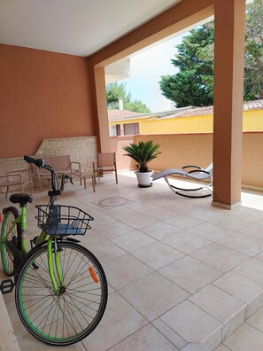 A covered patio area with a bicycle, chairs, and a potted plant. - Casalabate Apartment by CDA Accommodation (Squinzano)