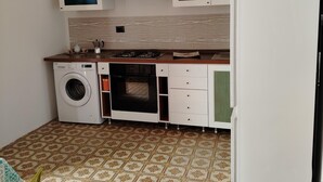 A compact kitchen with a washing machine, oven, and a refrigerator. - Casalabate Apartment by CDA Accommodation (Squinzano)