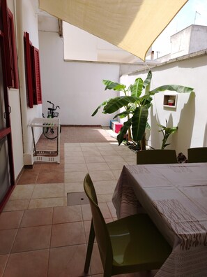 A patio area with a table and chairs, a bicycle, and a small table with a basket. - Casalabate Apartment by CDA Accommodation (Squinzano)