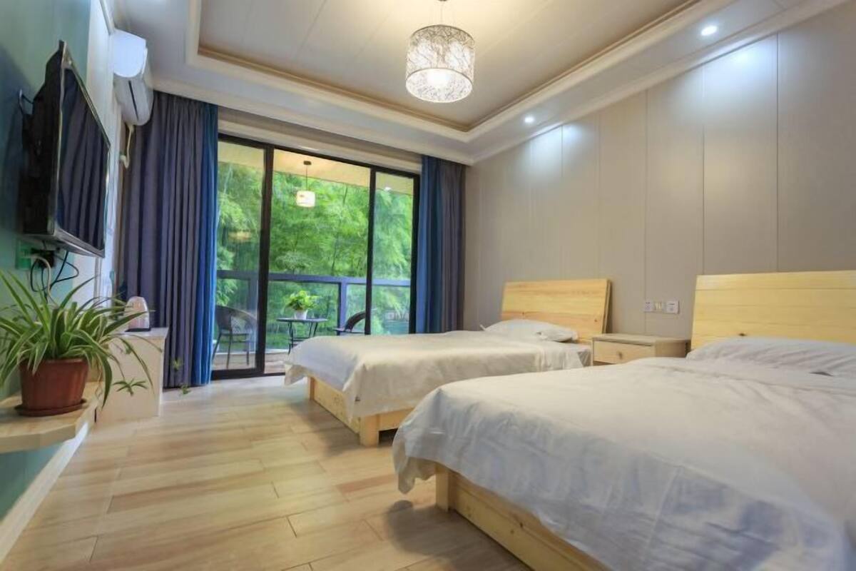 Une chambre d’hôtel avec deux lits, une télévision, un luminaire au plafond et une vue sur la verdure.