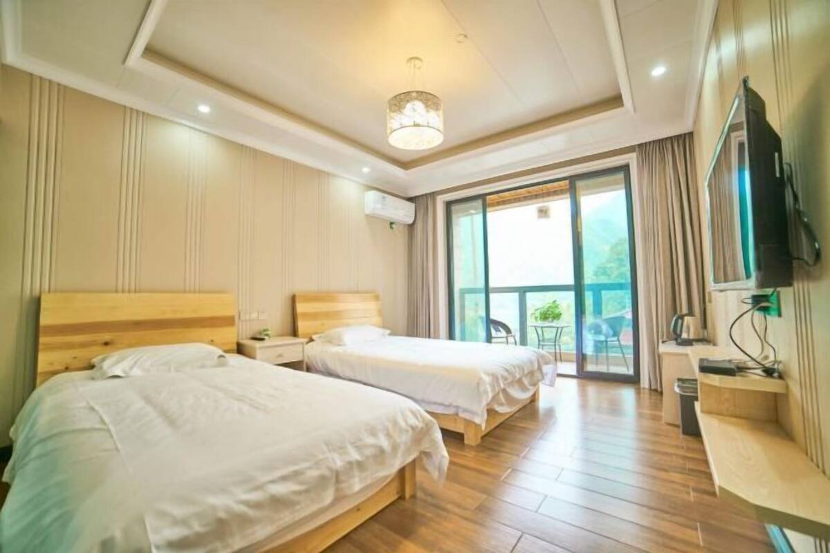 Une chambre d’hôtel avec deux lits, une télévision, un bureau et un balcon avec vue.