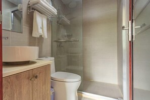 Une salle de bain comprenant des toilettes, un lavabo, un miroir et un espace douche.