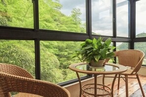 Une pièce dotée de grandes fenêtres, de meubles en osier et d’une plante en pot.