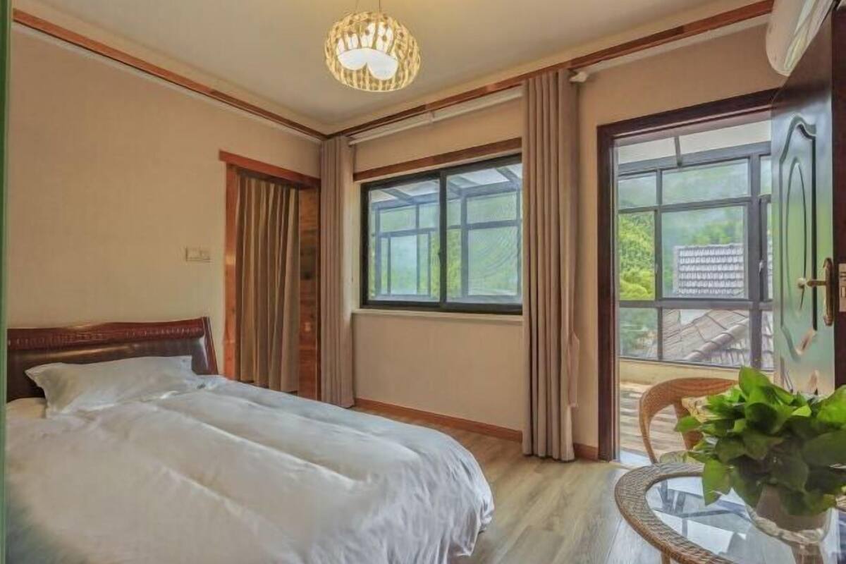 Une chambre avec un lit, une fenêtre, une porte et une chaise sur laquelle est posée une plante.