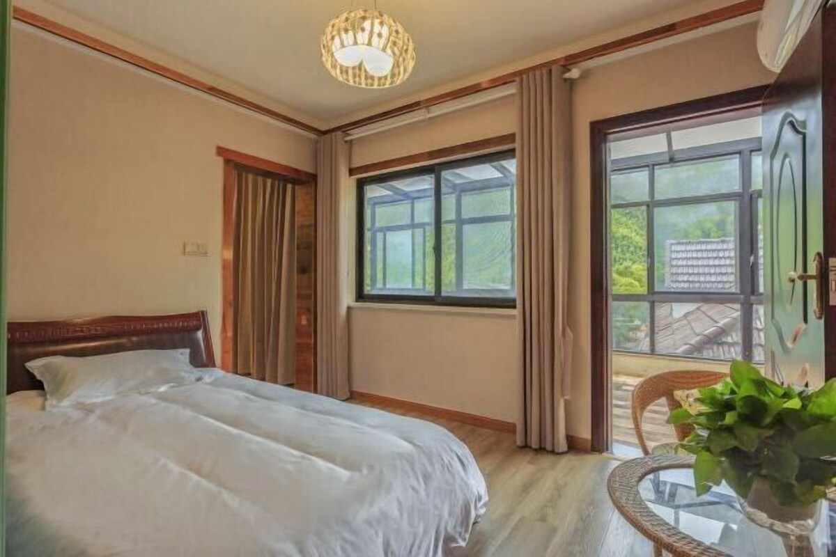 Une chambre à coucher avec un lit, une fenêtre avec des rideaux, une chaise et une plante en pot.