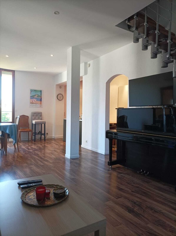 A spacious living area with a dining table, a piano, and a kitchen area.