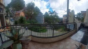 A balcony with a curved metal railing, a potted plant, and a small table. - RedDoorz Hostel @ Ritz Place Baguio (Baguio)