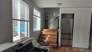 A spacious living area with a sofa, wooden flooring, a staircase, and a refrigerator. - Massage Chair, Tempurpedic Mattress, Amenity Claw Machine, 2 Story Loft House (Long Eddy)