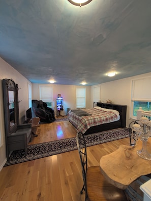 A spacious room with a large bed, a massage chair, a gaming console, and a wooden coffee table. - Massage Chair, Tempurpedic Mattress, Amenity Claw Machine, 2 Story Loft House (Long Eddy)