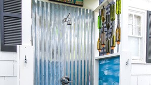 Puerta de metal corrugado con un panel azul, un picaporte metálico y una terraza de madera que conduce a ella.