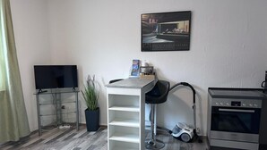 Ett modernt kök med en ugn från Bosch, en barstol, en väggmonterad TV och en krukväxt.