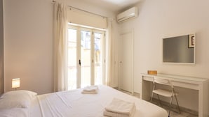 Une chambre d’hôtel avec un lit, un bureau, une chaise et une fenêtre avec des rideaux.